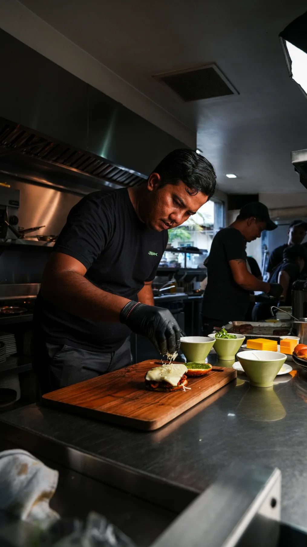 A chef adding cheese to a burger in the kitchen